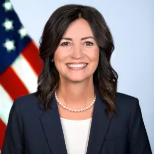 Dr. Michele Cantwell-Copher smiling with an American Flag in the background